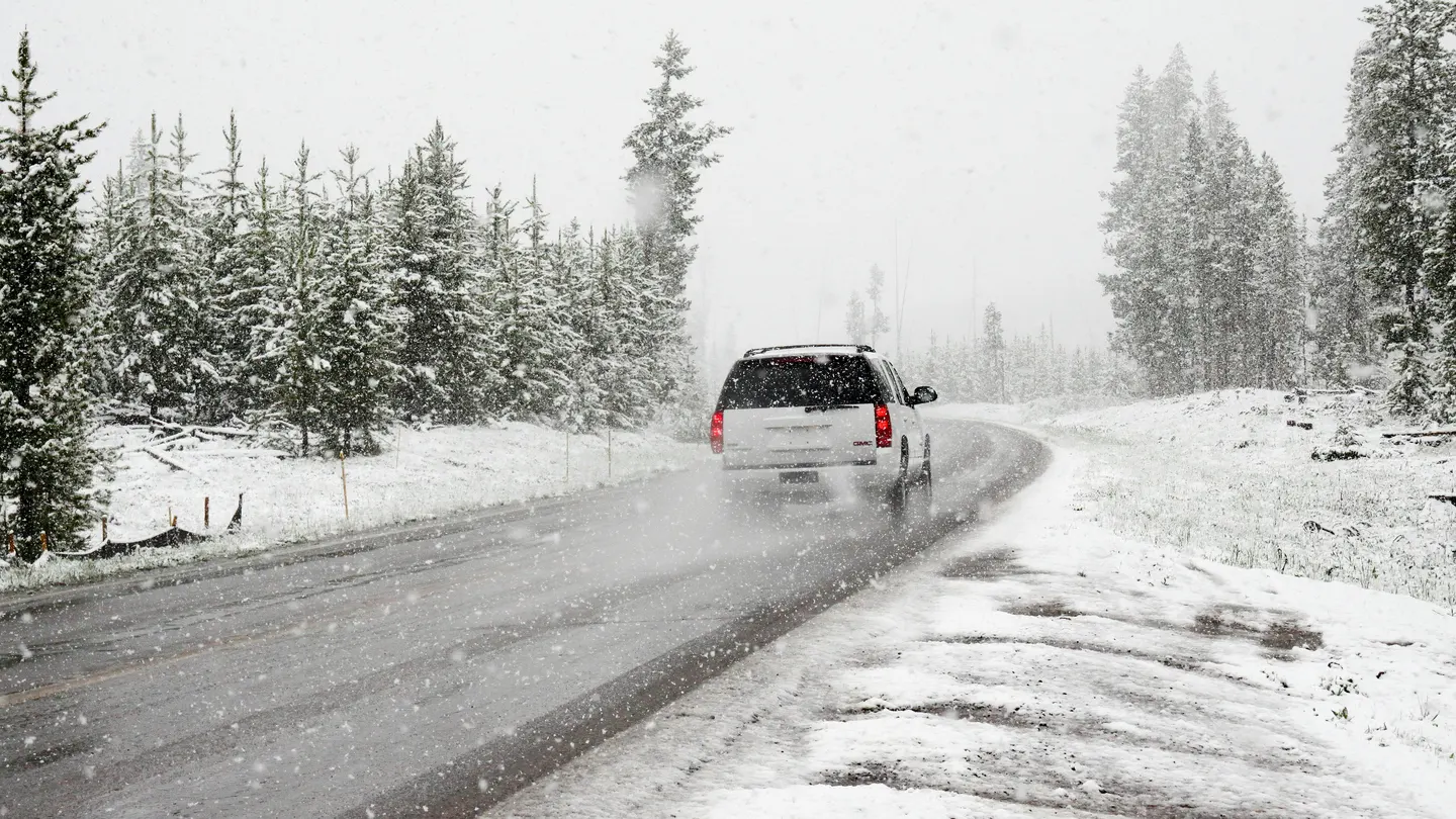 Un vehículo circulando por una carretera rodeada de nieve Un vehículo circulando por una carretera rodeada de nieve