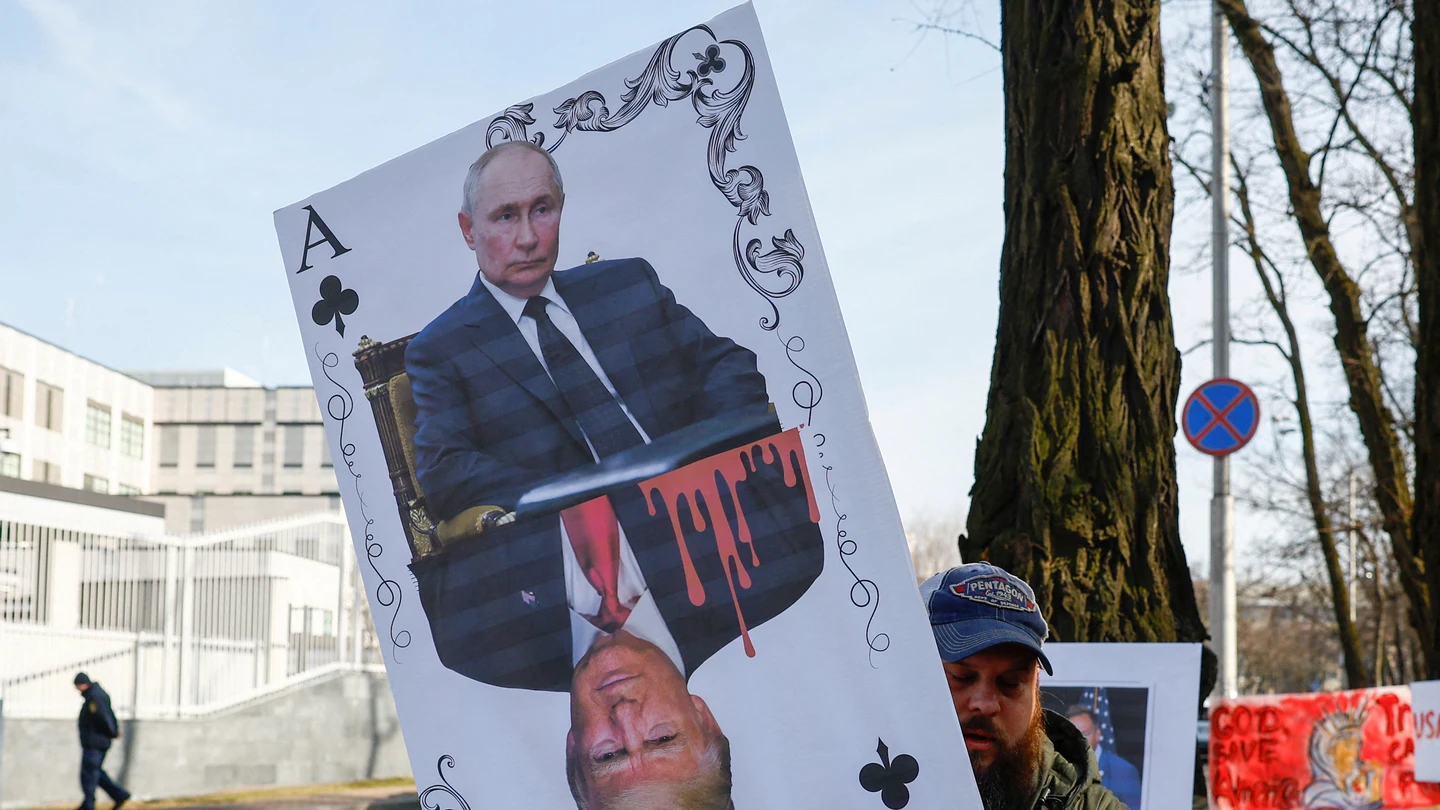 Un manifestante sostiene una pancarta que muestra una carta con los retratos de Putin y Donald Trump. Un manifestante sostiene una pancarta que muestra una carta con los retratos de Putin y Donald Trump.