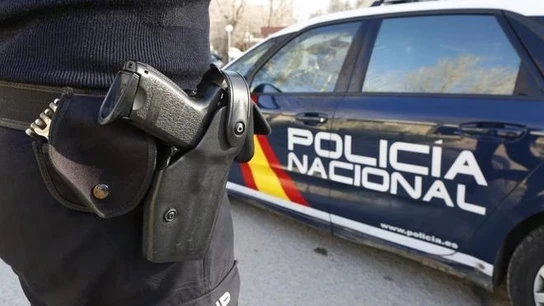 Imagen de archivo de un agente de la policía nacional y un coche de policía Imagen de archivo de un agente de la policía nacional y un coche de policía