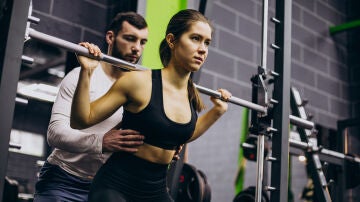 Una mujer realiza ejercicio con pesas junto a un entrenador personal