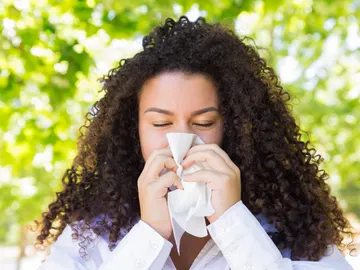 Mujer con alergia sonándose Mujer con alergia sonándose
