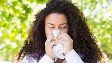 Mujer con alergia sonándose Mujer con alergia sonándose