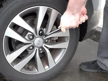 Hombre aflojando la rueda del coche Hombre aflojando la rueda del coche