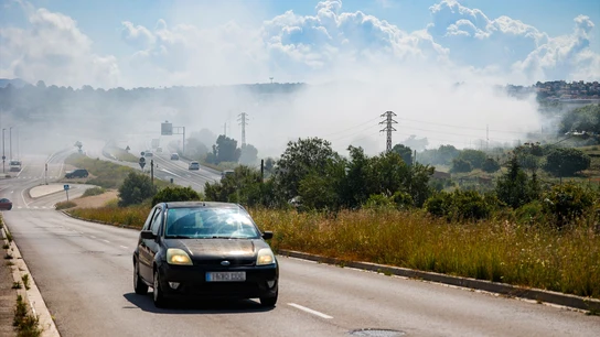 Un coche deja atrás la nube tóxica producida por el incendio de una fábrica de productos químicos en Barcelona. Un coche deja atrás la nube tóxica producida por el incendio de una fábrica de productos químicos en Barcelona.