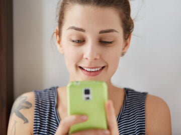 Una mujer consulta el tel&eacute;fono m&oacute;vil