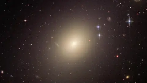 Las galaxias tempranas contribuyen al 'resplandor' del universo La enorme galaxia elíptica ESO 325-G004 brilló 10.000 veces más cuando se formó que hoy. Este tipo de galaxias iluminó brevemente todo el universo y contribuyó a la radiación de fondo que podemos medir hoy. REMITIDA / HANDOUT por NASA, ESA AND THE HUBBLE HERITAGE TEAM (STSCI/AURA Fotografía remitida a medios de comunicación exclusivamente para ilustrar la noticia a la que hace referencia la imagen, y citando la procedencia de la imagen en la firma 12/05/2025
