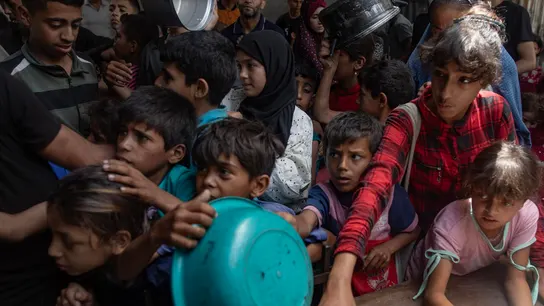 Menores gazatíes esperan por un plato de comida Menores gazatíes esperan por un plato de comida