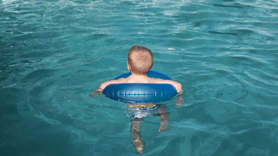 Un niño en una piscina con un flotador  Un niño en una piscina con un flotador