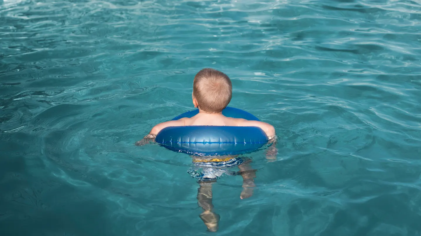 Un niño en una piscina con un flotador Un niño en una piscina con un flotador