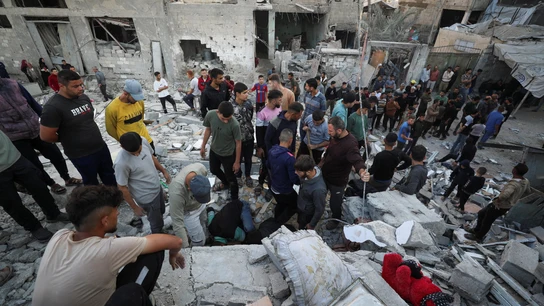 Gazatíes alrededor de los escombros de un edificio derruido por Israel Gazatíes alrededor de los escombros de un edificio derruido por Israel