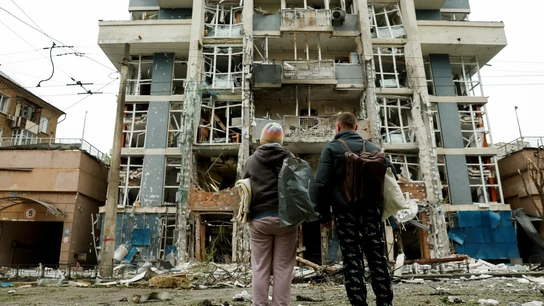 Dos personas observan un edificio destruido por las bombas de Rusia Dos personas observan un edificio destruido por las bombas de Rusia