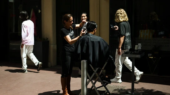 Una peluquera corta al pelo a un cliente en la calla tras el apagón en Cannes.  Una peluquera corta al pelo a un cliente en la calla tras el apagón en Cannes.
