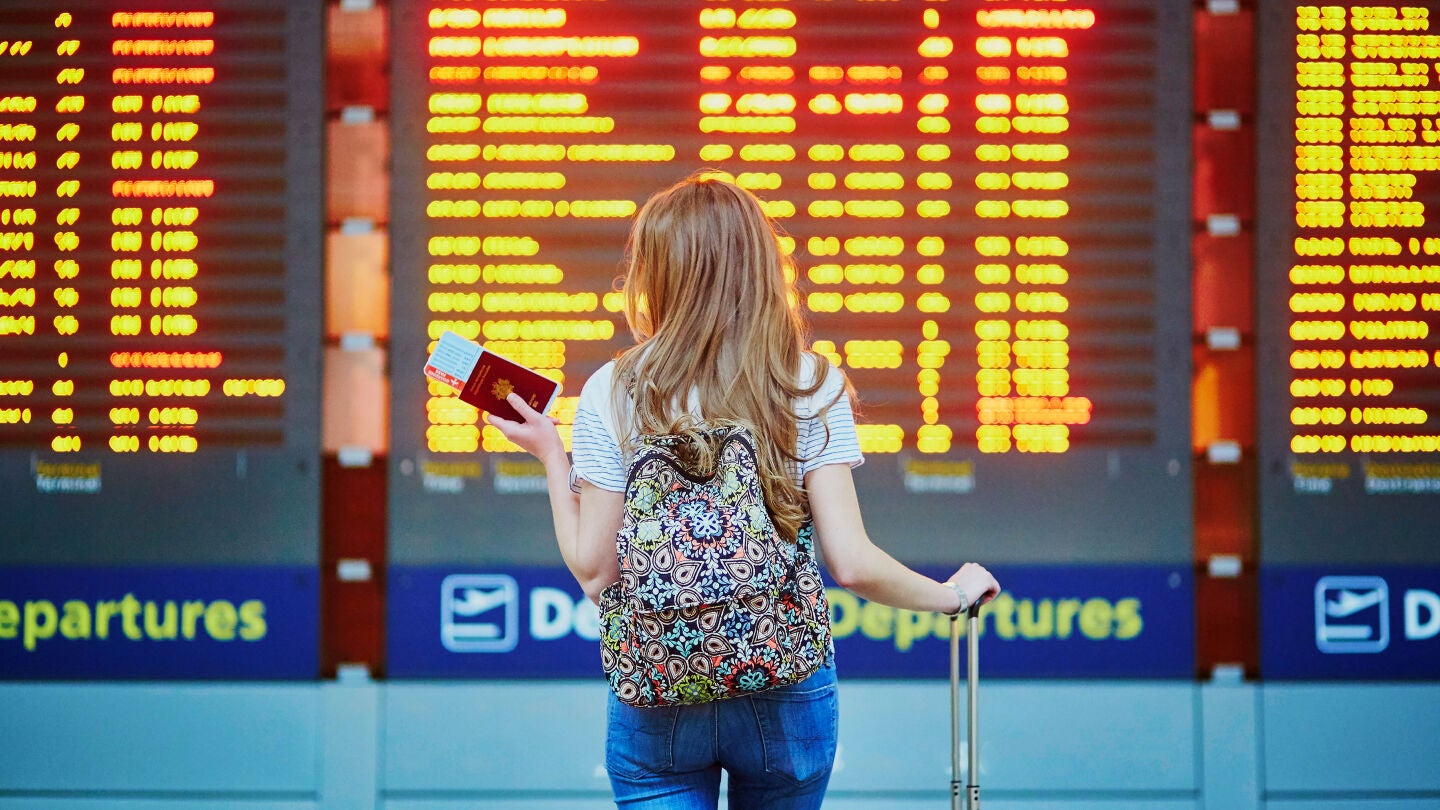 Chica mirando los vuelos retrasados en el aeropuerto