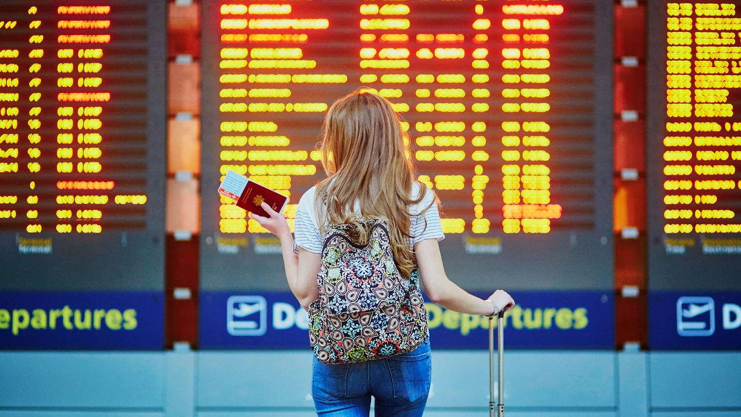 Chica mirando los vuelos retrasados en el aeropuerto Chica mirando los vuelos retrasados en el aeropuerto