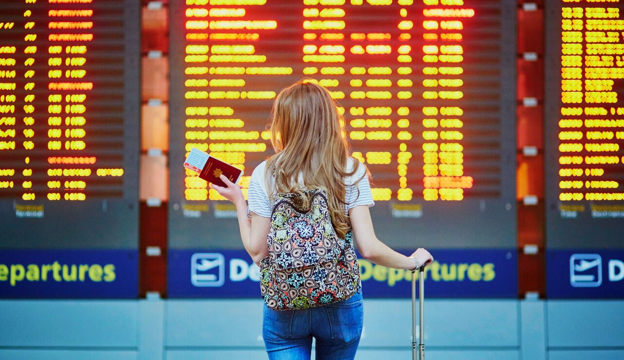 Chica mirando los vuelos retrasados en el aeropuerto