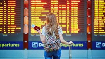 Chica mirando los vuelos retrasados en el aeropuerto