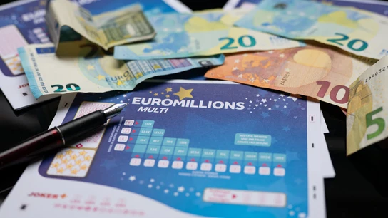 Varias participaciones de Euromillones rodeadas de varios billetes Varias participaciones de Euromillones rodeadas de varios billetes