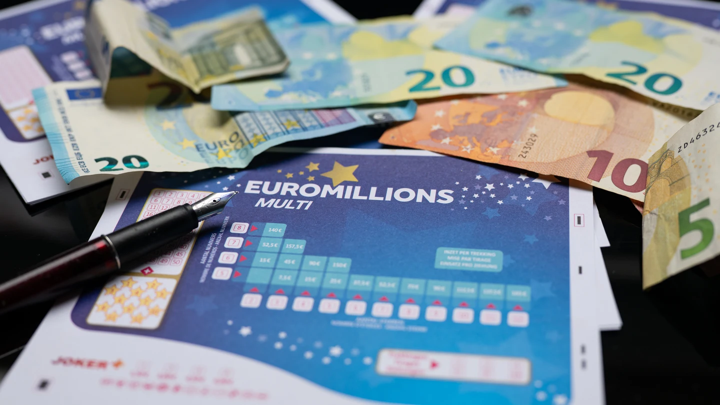 Varias participaciones de Euromillones rodeadas de varios billetes Varias participaciones de Euromillones rodeadas de varios billetes