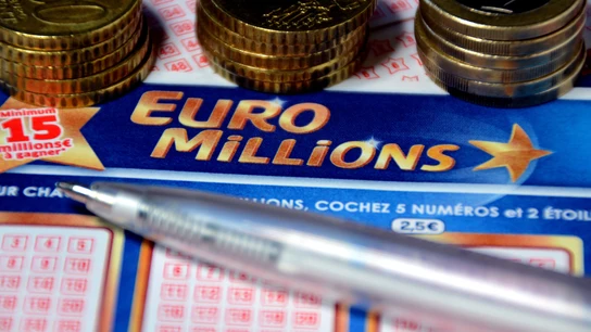 Una participación de Euromillones junto a varias monedas de 50 céntimos de euro Una participación de Euromillones junto a varias monedas de 50 céntimos de euro