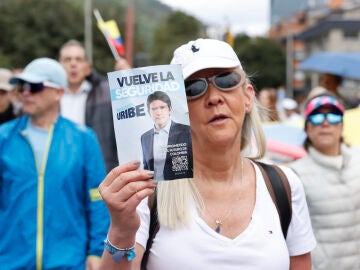 na mujer sostiene un cartel durante una caminata por la paz y en apoyo a Miguel Uribe Turbay en Bogotá