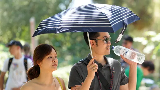 Dos personas se protegen del sol con un paraguas Dos personas se protegen del sol con un paraguas