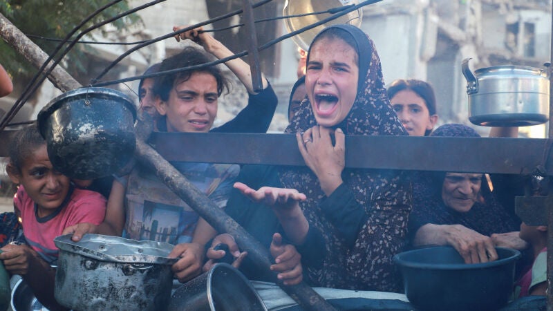 Palestinos esperan recibir comida en la ciudad de Gaza.