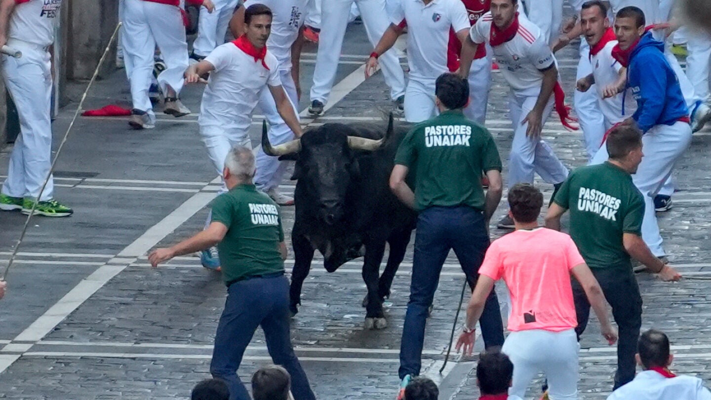 Uno de los toros de la ganadería Cebada Gago se queda retrasado y los pastores intentan reconducirlo durante el segundo encierro de los Sanfermines este martes, en Pamplona.