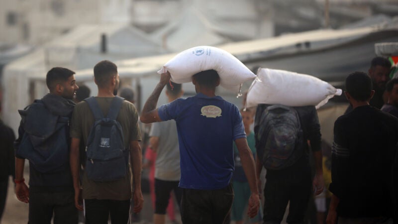 Palestinos cargan sacos de harina entregados por camiones de ayuda humanitaria en la ciudad de Gaza