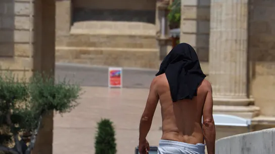 Un hombre utiliza su camiseta para resguardarse del calor. Un hombre utiliza su camiseta para resguardarse del calor.