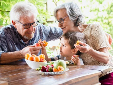 Unos abuelos comiendo fruta junto a su nieta