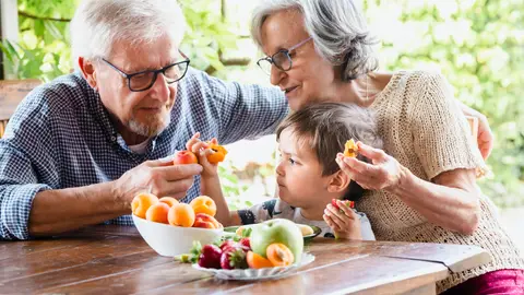 Unos abuelos comiendo fruta junto a su nieta Unos abuelos comiendo fruta junto a su nieta