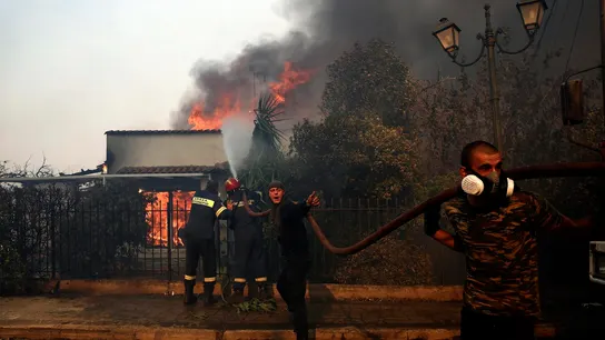 Bomberos y voluntarios griegos luchan contra el fuego en una casa Bomberos y voluntarios griegos luchan contra el fuego en una casa