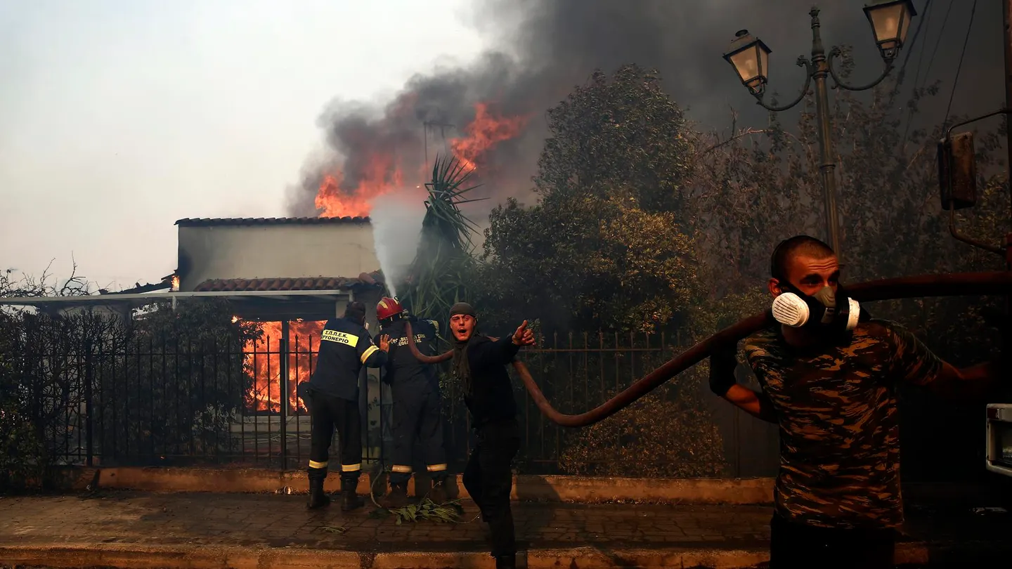 Bomberos y voluntarios griegos luchan contra el fuego en una casa Bomberos y voluntarios griegos luchan contra el fuego en una casa