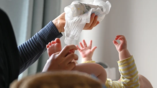 Una madre, cambiando el pañal a su bebé en un cambiador en Leipzig Una madre, cambiando el pañal a su bebé en un cambiador en Leipzig