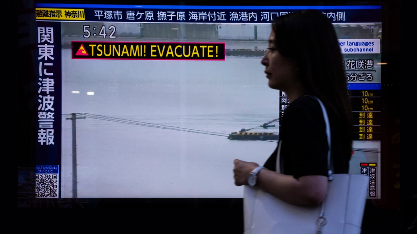 Una mujer pasa ante una televisión con una alerta por tsunami tras el terremoto en Rusia Una mujer pasa ante una televisión con una alerta por tsunami tras el terremoto en Rusia