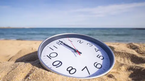 Reloj sobre la arena de una playa Reloj sobre la arena de una playa