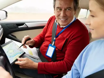 Profesor de autoescuela muestra indicaciones a una alumna Profesor de autoescuela muestra indicaciones a una alumna