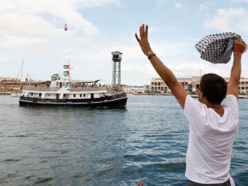 Un hombre despedía a los barcos que forman parte de la flotilla desde el puerto de Barcelona el domingo.