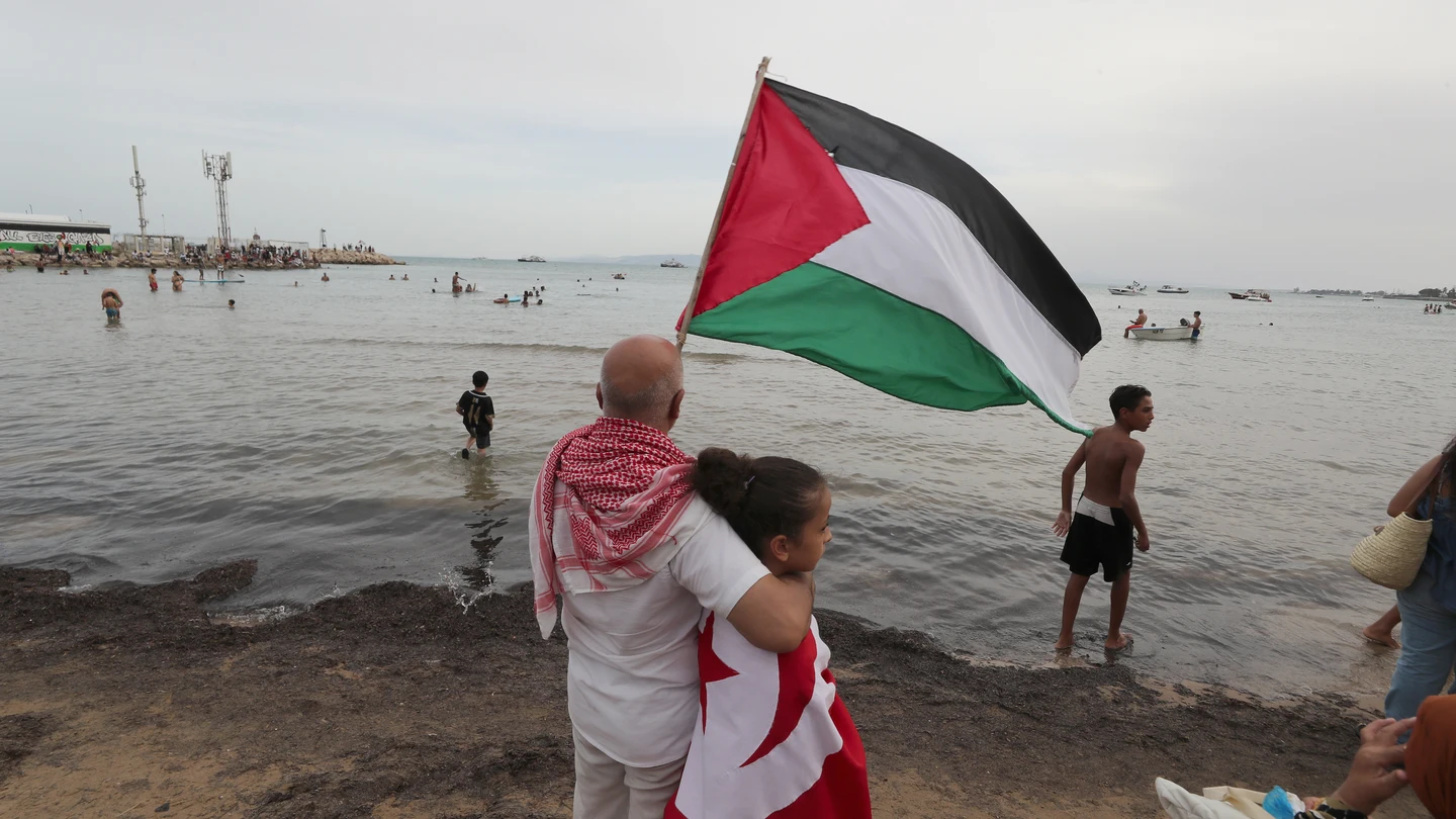 Un hombre con una bandera palestina junto a una niña, con una tunecina, a la espera de la llegada de la Global Sumud Flotilla a Túnez Un hombre con una bandera palestina junto a una niña, con una tunecina, a la espera de la llegada de la Global Sumud Flotilla a Túnez