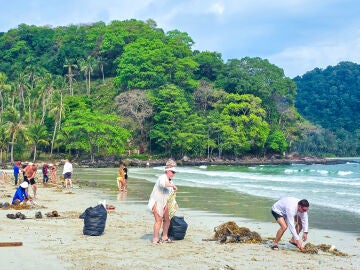 Turismo solidario con gente limpiando una playa