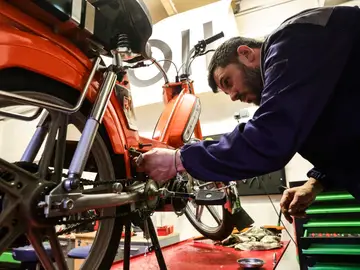 Un mecánico da los últimos toques para convertir una moto de combustión en una moto eléctrica en Francia. Un mecánico da los últimos toques para convertir una moto de combustión en una moto eléctrica en Francia.