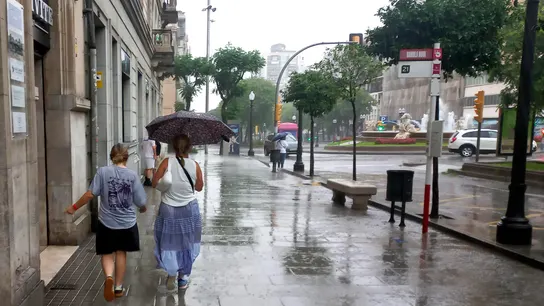 Dos personas protegiéndose de la lluvia bajo un paraguas en el centro de Tarragona Dos personas protegiéndose de la lluvia bajo un paraguas en el centro de Tarragona