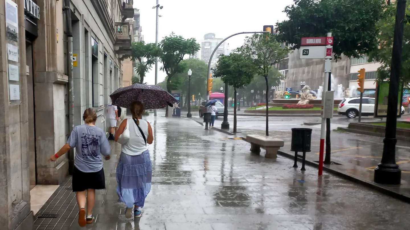 Dos personas protegiéndose de la lluvia bajo un paraguas en el centro de Tarragona Dos personas protegiéndose de la lluvia bajo un paraguas en el centro de Tarragona