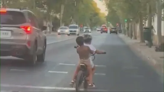 Dos niños circulan sin casco en una bici eléctrica por una concurrida avenida de Sevilla: "Vamos a casa" Dos niños circulan sin casco en una bici eléctrica por una concurrida avenida de Sevilla: "Vamos a casa"