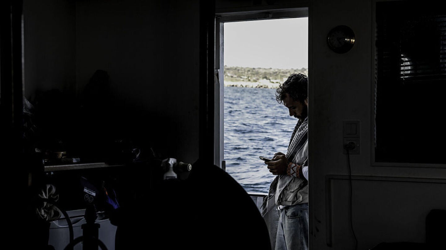 Imagen de Thiago Ávila a bordo de la Global Sumud Flotilla usando el móvil, en un contraste de luces.