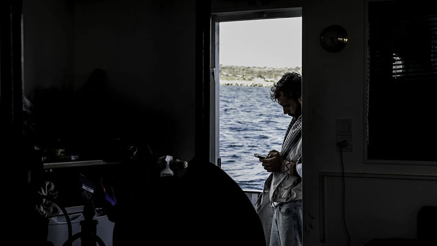 Imagen de Thiago Ávila a bordo de la Global Sumud Flotilla. Imagen de Thiago Ávila a bordo de la Global Sumud Flotilla usando el móvil, en un contraste de luces.