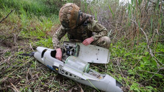Un soldado ruso inspeciona los restos de un dron.