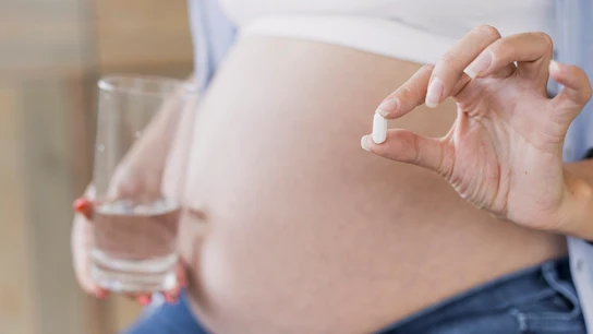 Una mujer embarazada, tomando una pastilla de paracetamol Una mujer embarazada, tomando una pastilla de paracetamol
