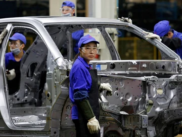 Una trabajadora observa desde una línea de montaje de BYD en Shenzhen, China. Una trabajadora observa desde una línea de montaje de BYD en Shenzhen, China.