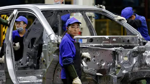 Una trabajadora observa desde una línea de montaje de BYD en Shenzhen, China. Una trabajadora observa desde una línea de montaje de BYD en Shenzhen, China.